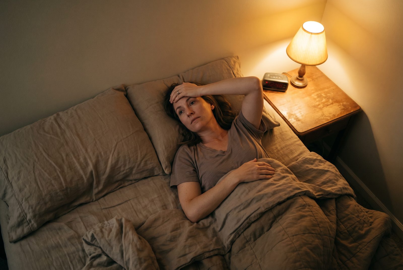 A person lying awake in bed at 3 a.m., checking their phone